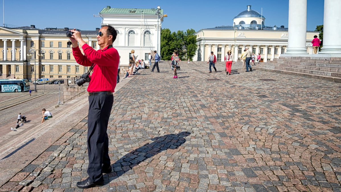 Mies kuvaa tuomiokirkon portailta.