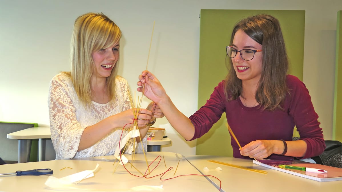 Jenna Rosenberg (vasemmalla) tekemässä yhdessä opiskelijatoverinsa kanssa spagetti-vaahtokarkki-rakennelmaa.