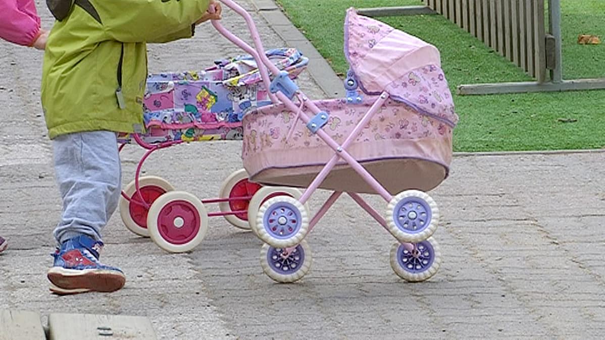 Lapsi ja nukenrattaat päiväkodin pihalla