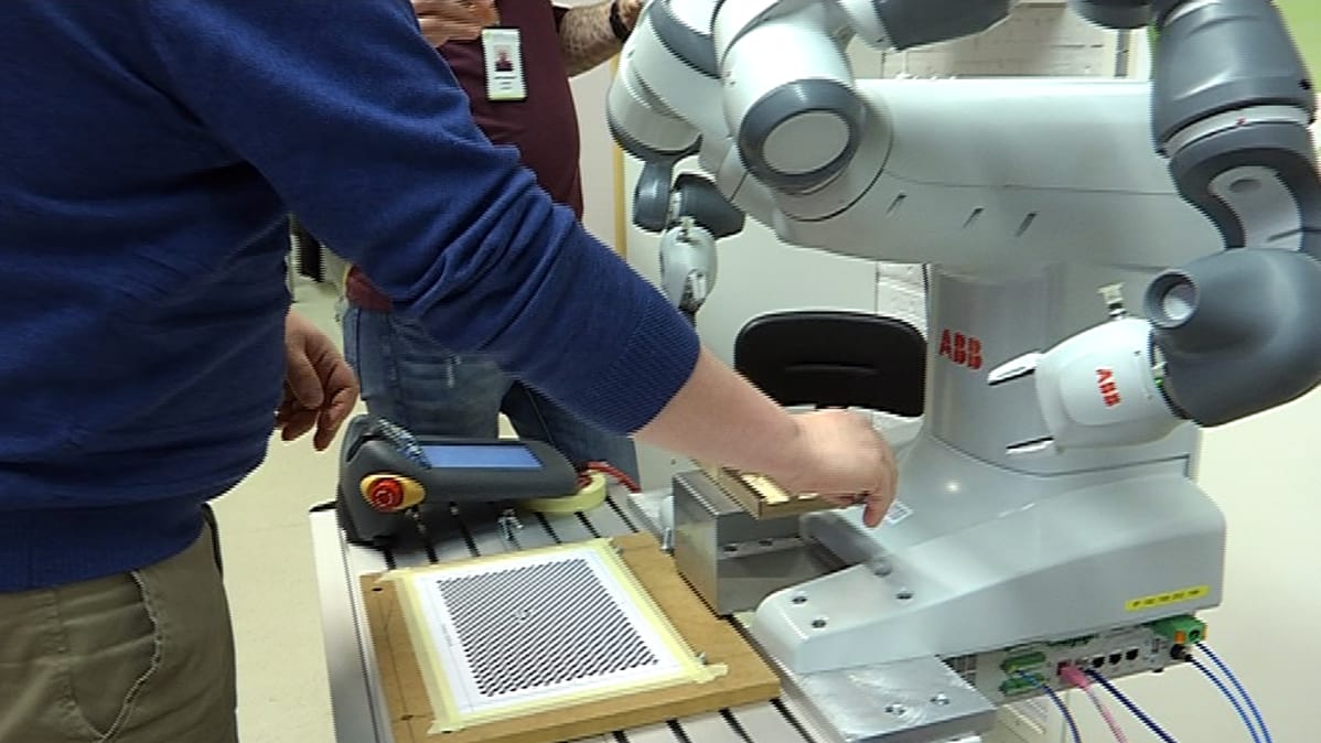 Ihminen tekee työtä yhdessä robotin kanssa.