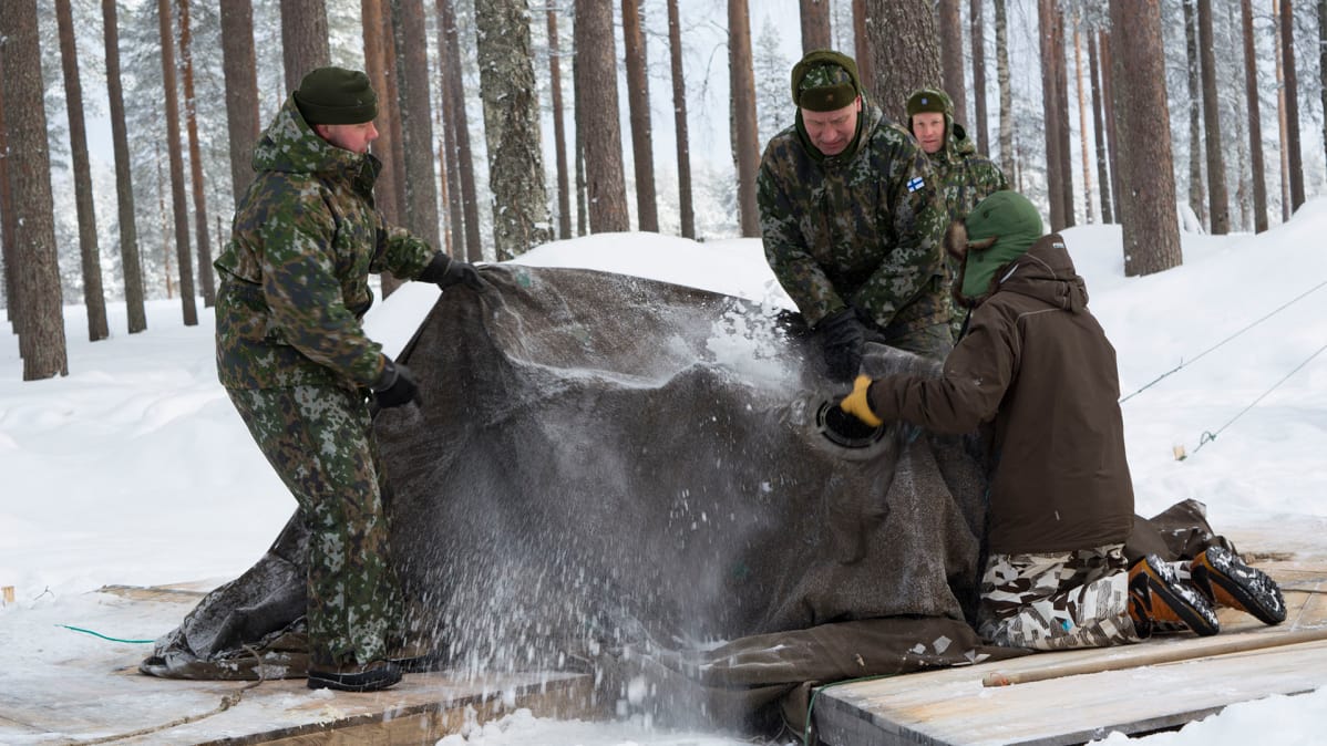 Miehet purkavat puolijoukkuetelttaa