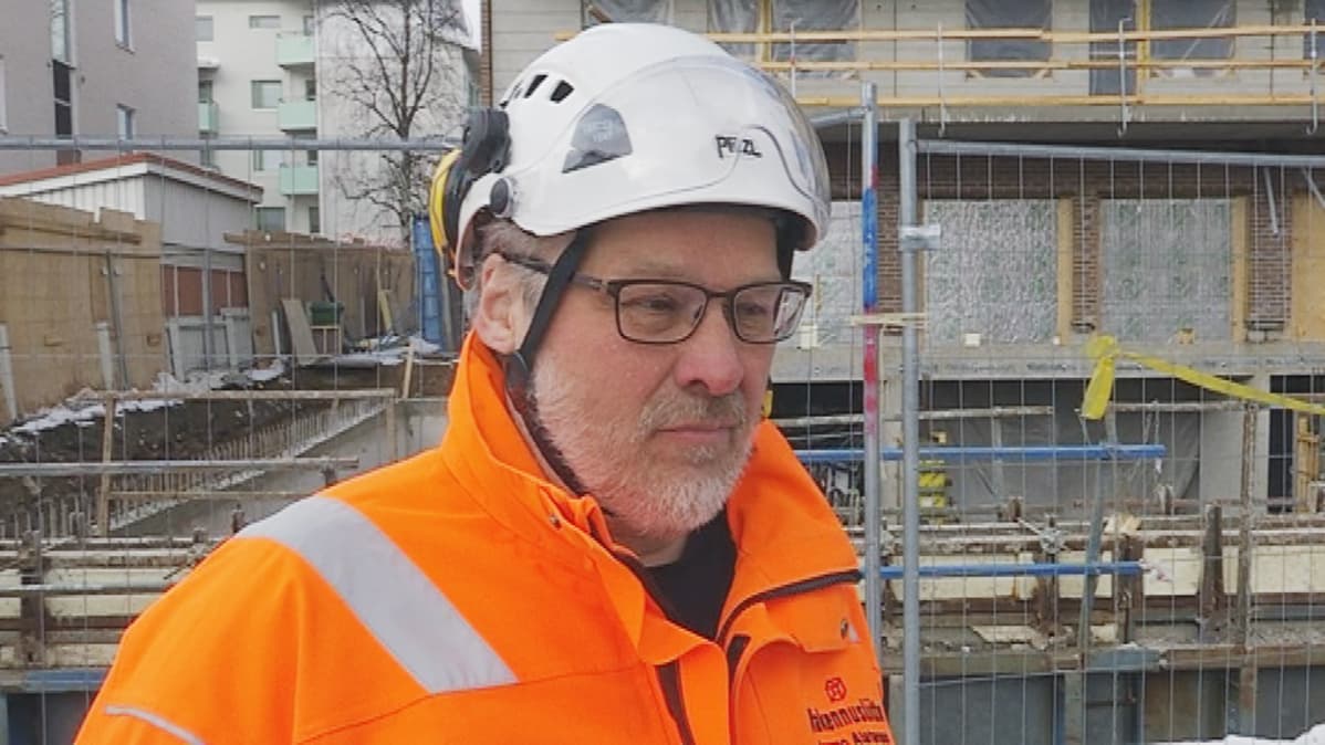 Rakennusliiton aluetoimitsija Jarmo Alatarvas suojavarustuksessa Asunto Oy Ruokasenpuistikon työmaan edessä.