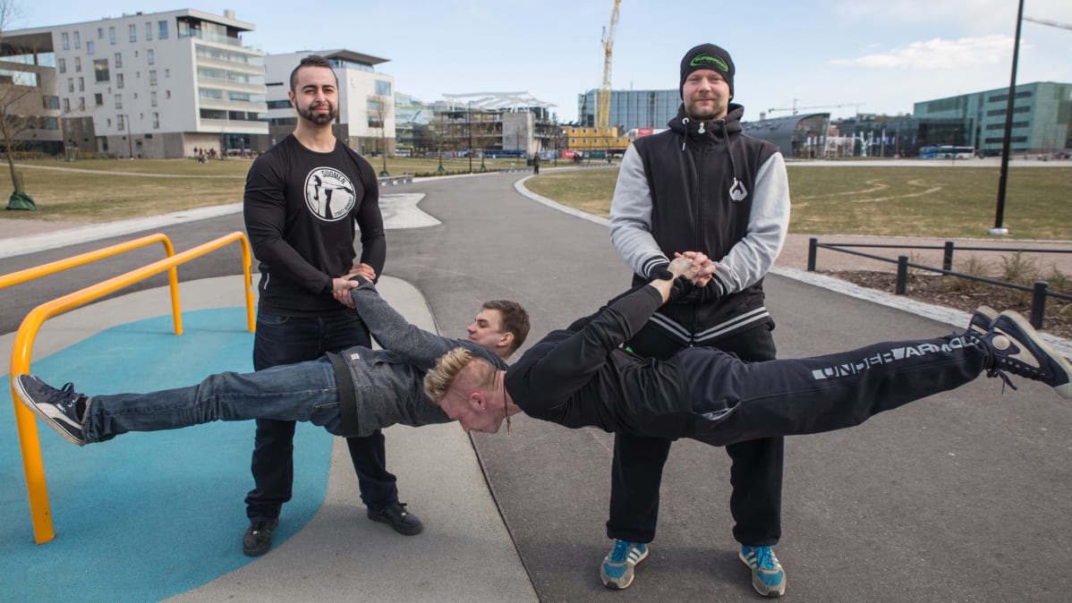 Kaksi miestä pitää kahta street workout treenaajaa ilmassa.