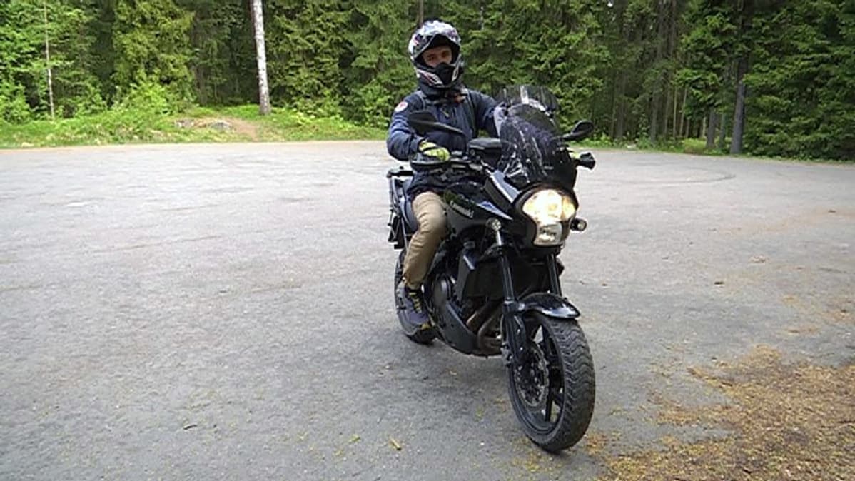 Nuori mies moottoripyörällä parkkipaikalla