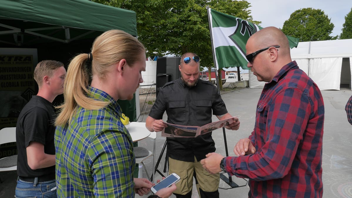 Pohjoismainen vastarintaliikkeen edustajat seisoskelevat teltallaan odottamassa kiinnostuneita.