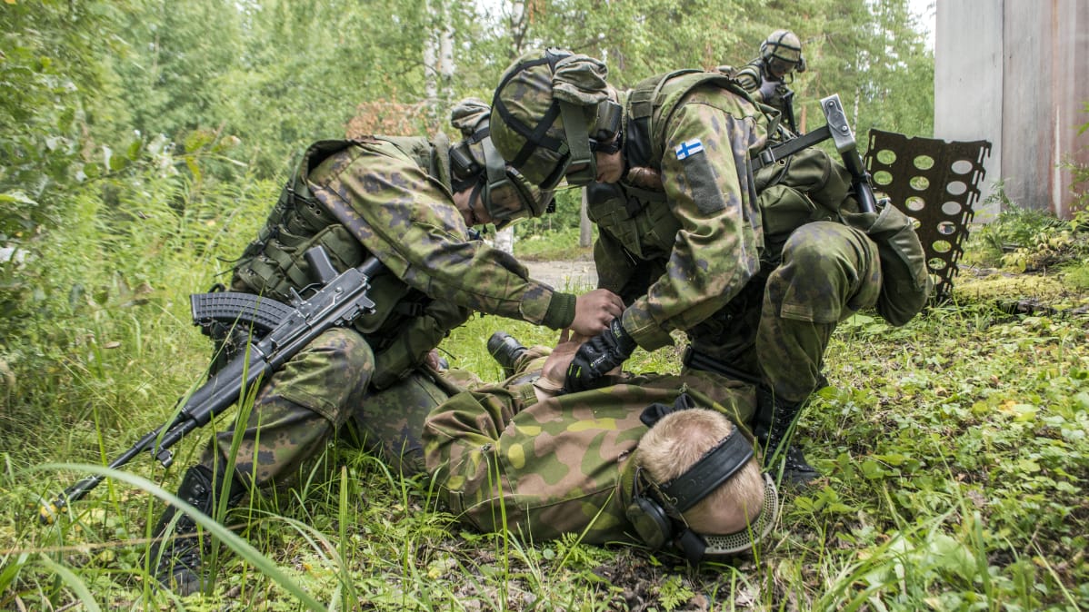 Sotilaspoliisit raudoittaa maalihenkilöä taisteluharjoituksessa.