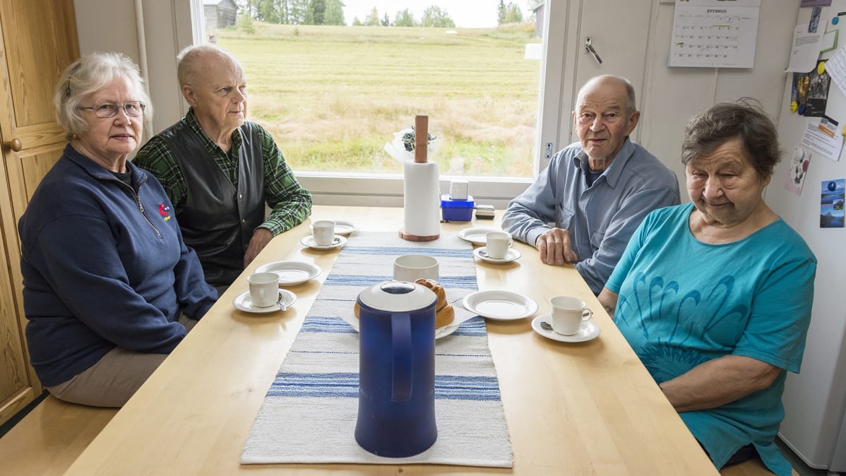 Kaksi naista ja kaksi miestä istuvat kahvipöydän ääressä.