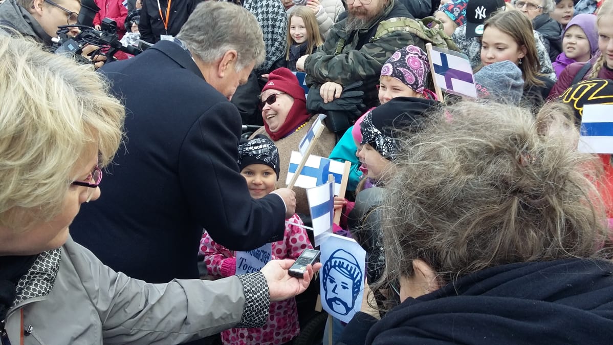 Niinistö tervehtii yleisöä.