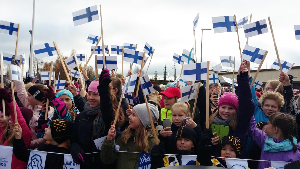 Lapset heiluttavat Suomen lippuja.