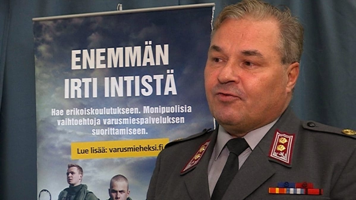 Everstiluutnatti seisoo Enemmän irti intistä-taulun vieressä