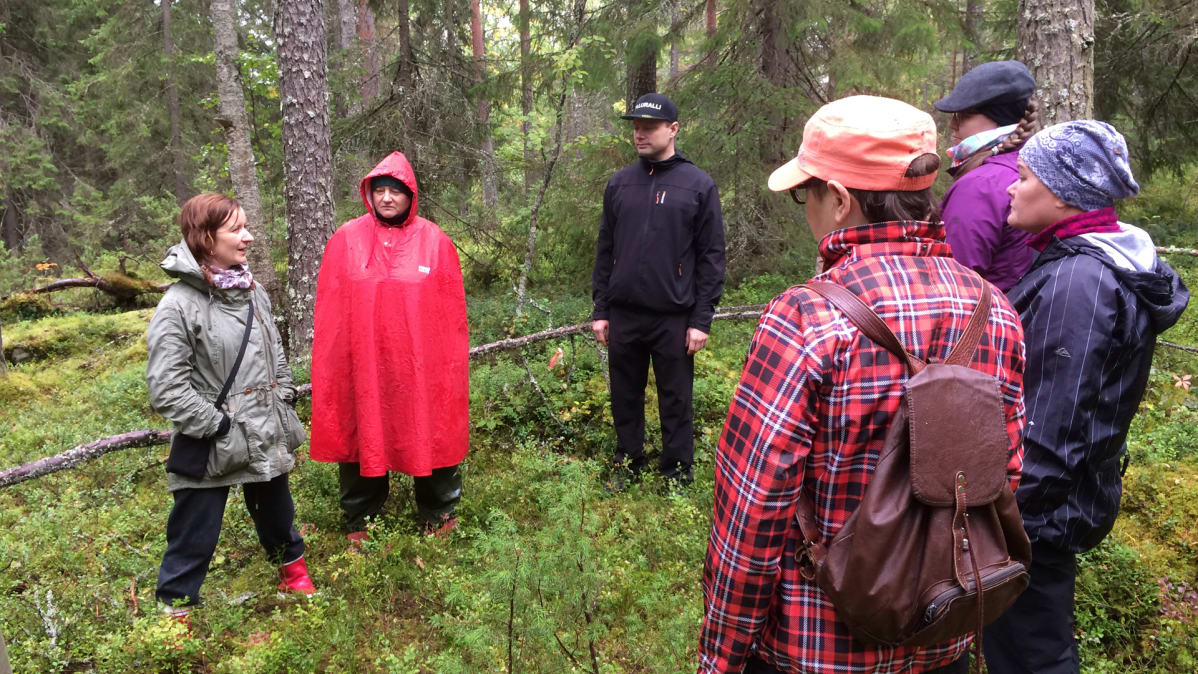 Ryhmä ihmisiä seisoo metsässä.