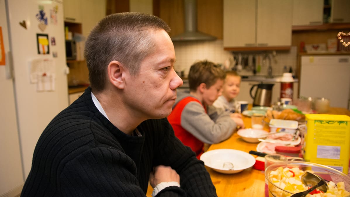 Isä istuu aamupalapöydässä kahden pienen pojan kanssa.