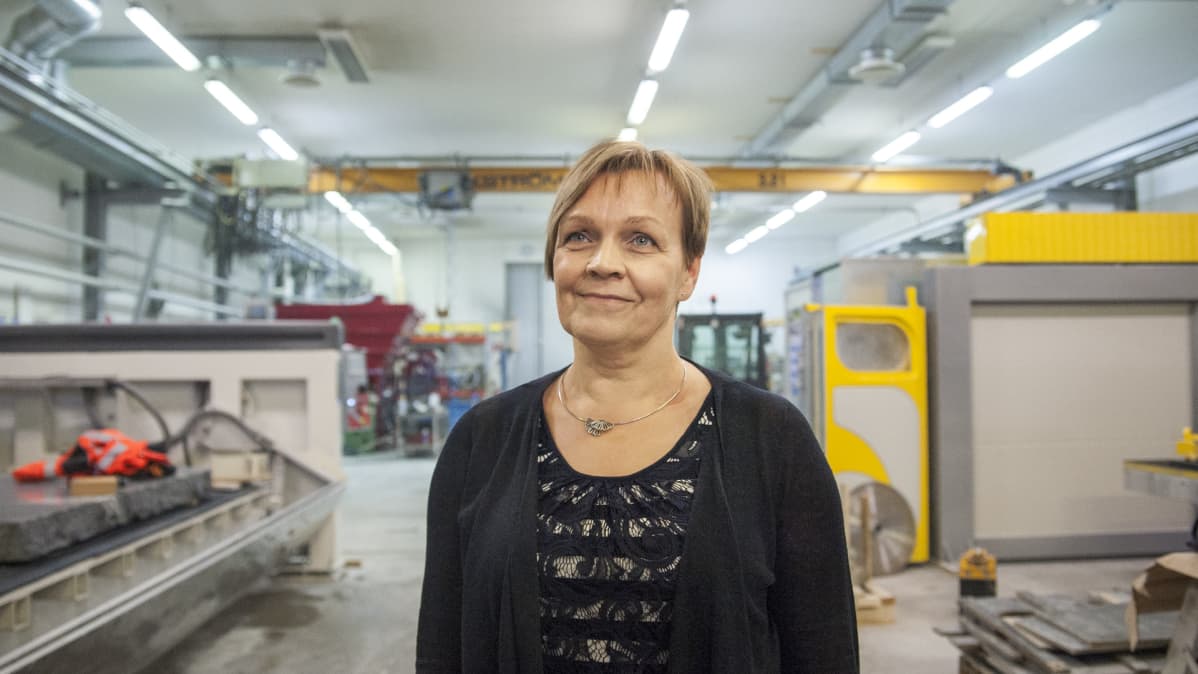 Sari Marttila seisoo tehtaassa.