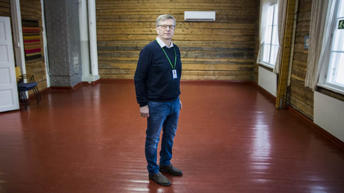 Mies seisoo vanhan koulun suuren salin keskellä.