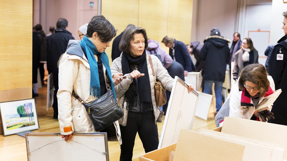 Kaksi naista katselee teoksia Postin taidemyyntitapahtumassa.