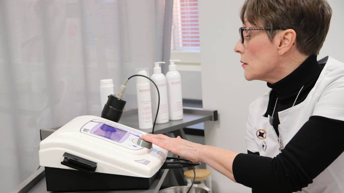 Kauneudenhoitoalan lehtori Outi Tukki säätää radiofrekvenssilaitetta