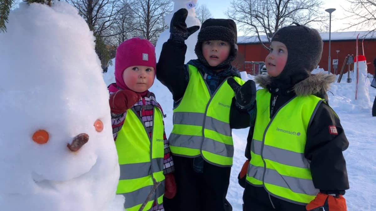 Lapset ihastelevat lumiukkoa.