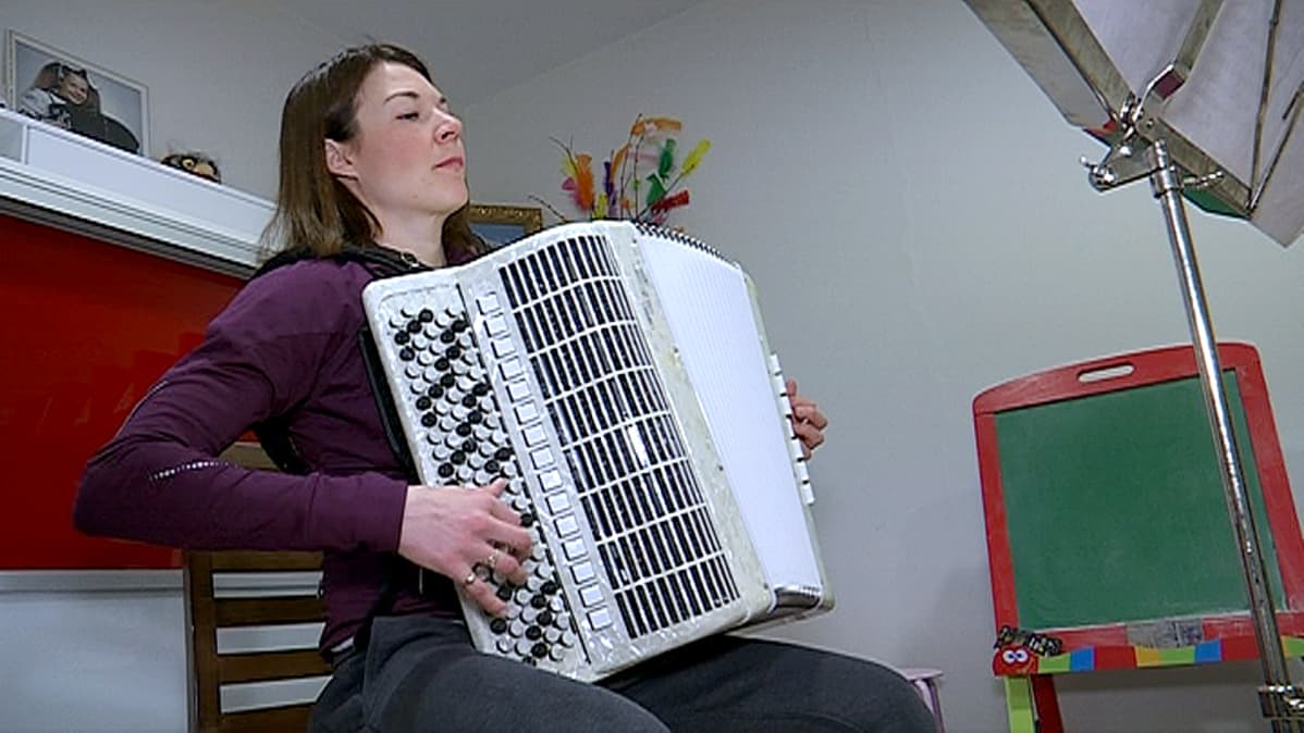 Mona-Liisa Nousiainen soittaa kotonaan harmonikkaa.