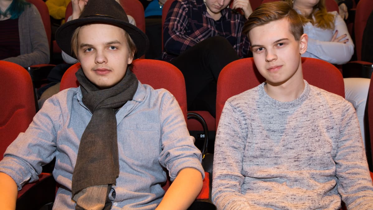 Nuoret miehet teatterin katsomossa.