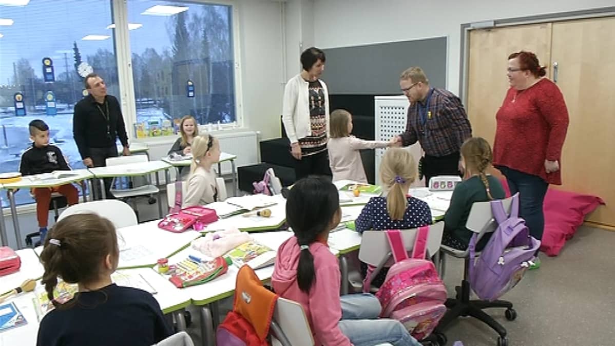 Sami Virta ja Jaana Nordlund kättelemässä oppilaita luokkahuoneessa.