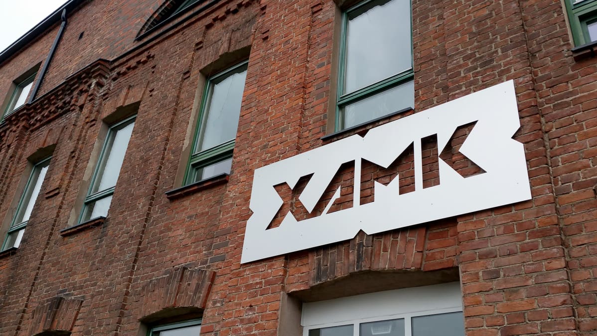 Xamkin tunnus Kouvolan kampuksen tiiliseinässä.