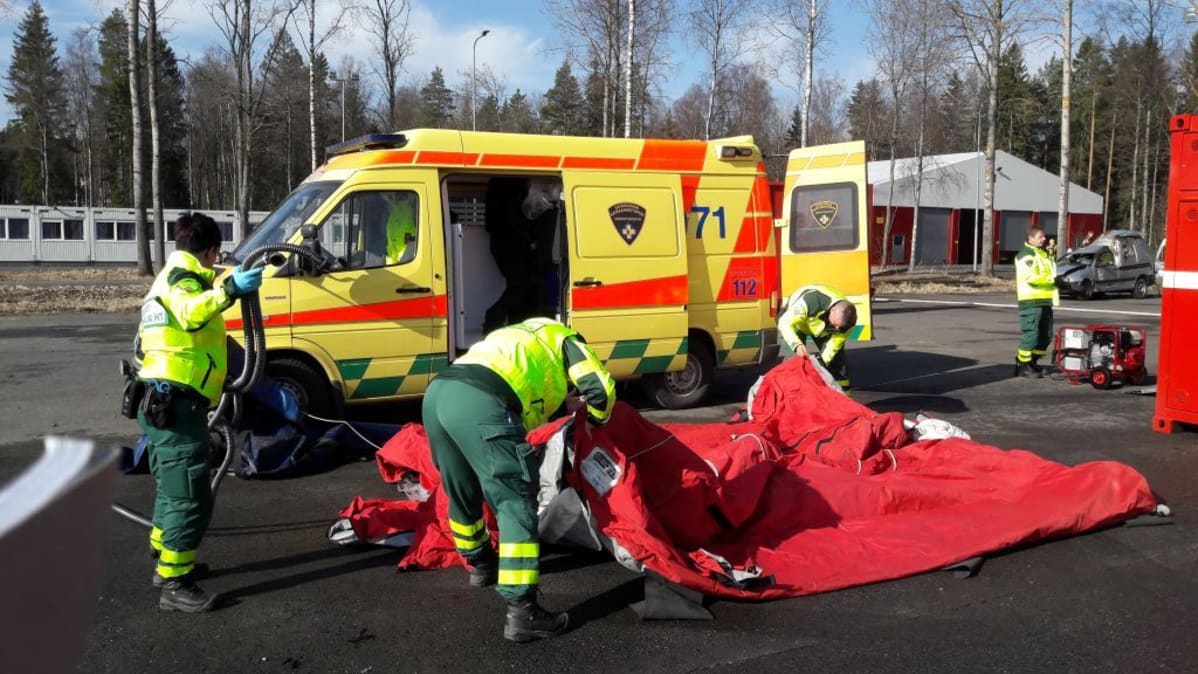 Ampulanssimiehet pystyttävät ensiaputelttaa.