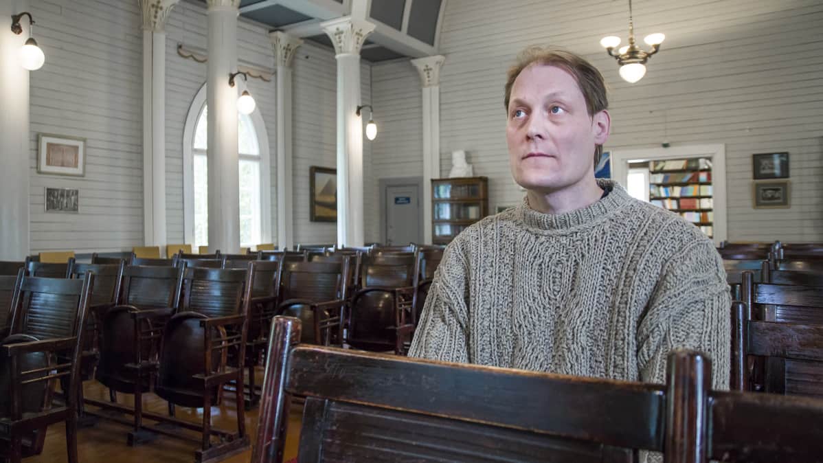 Pekka Ervast -temppelin entinen vahtimestari Sampsa Kuukasjärvi istuu penkillä.