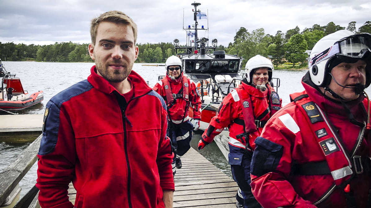 Fredrik Stenius seisoo laiturilla. Muut Meripelastusseuran jäsenet kiirehtivät hänen ohitseen.