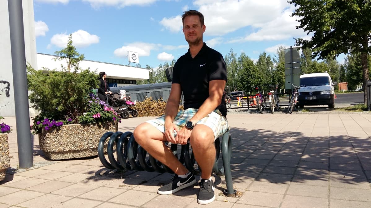 Iisalmen kaupungin viher- ja liikunta-alue päällikkö Harri Honkanen istuu tyhjän pyörätelineen päällä.