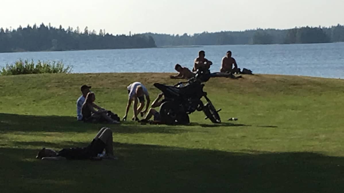 Ihmisiä istumassa uimarannalla Kuhmossa.