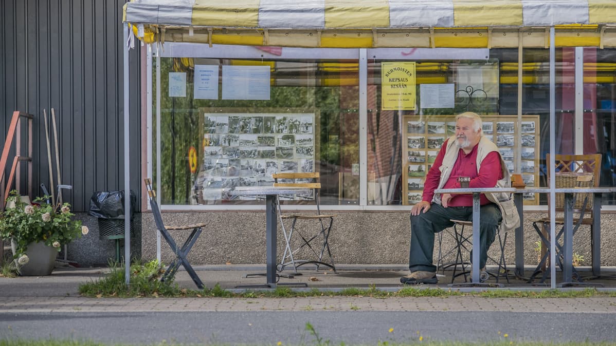 Mies istuu baarin edessä.
