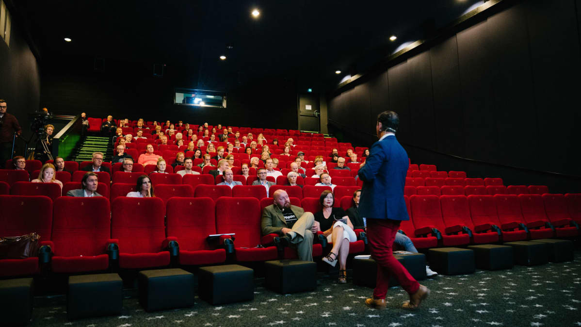 Speakersforumin André Noël Chaker rohkaisee yleisöä ennen elokuvaa voittamaan puhumisenpelkonsa.