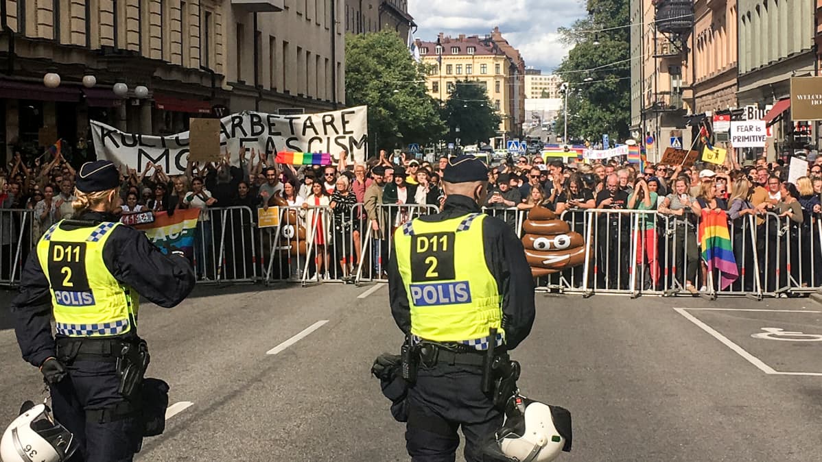 ihmisiä mielenosoituksessa katuaitojen takana