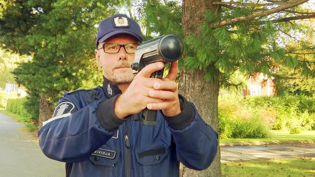 Poliisi mittaa käsitutkalla nopeuksia.