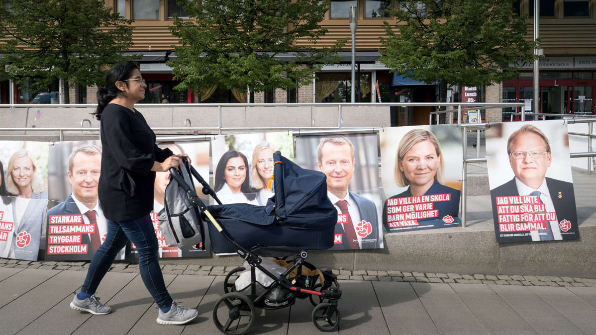 Ninel Barrios Pizarro kävelee lastenvaunujen kanssa - vaalimainoksia taustalla.