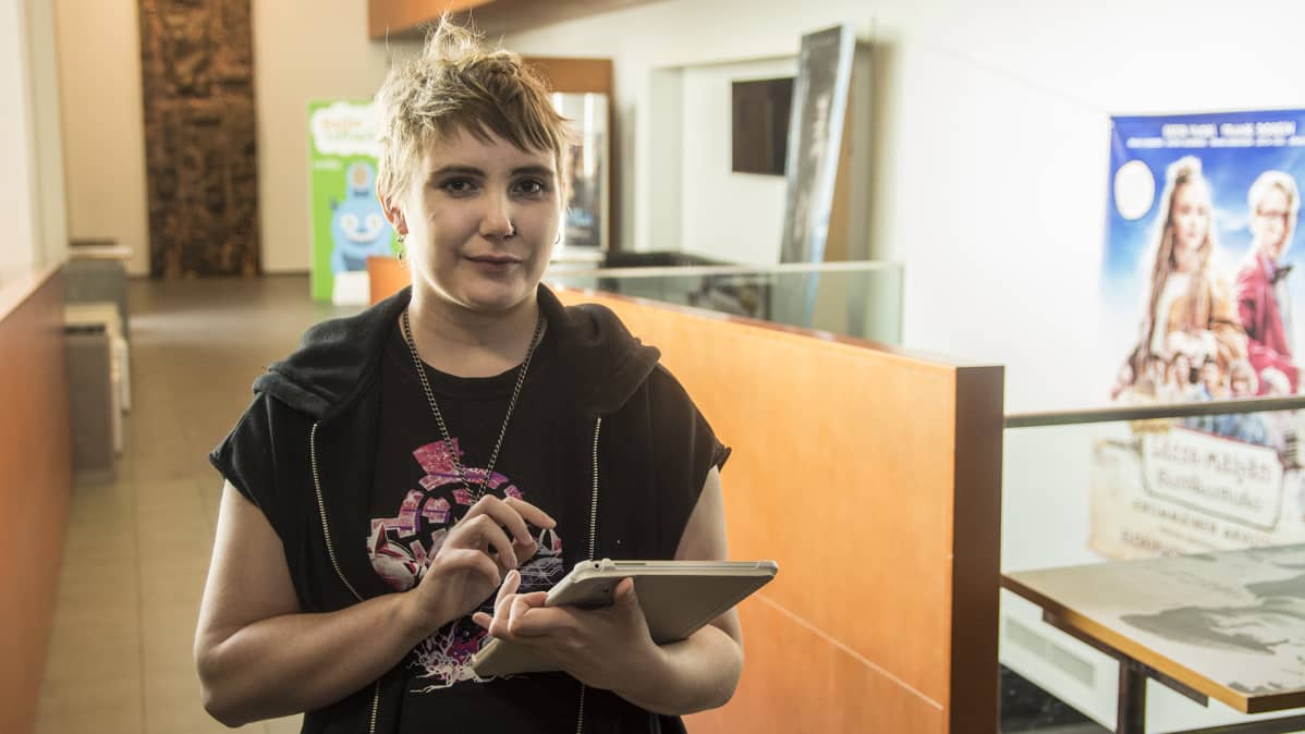 Nuori nainen pitää käsissään tablet-tietokonetta.