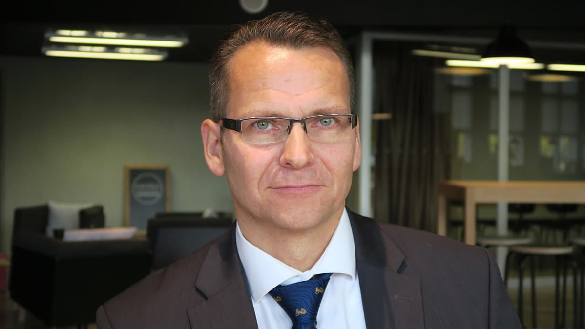 Silmälasipäinen mies poseeraa kameralle
