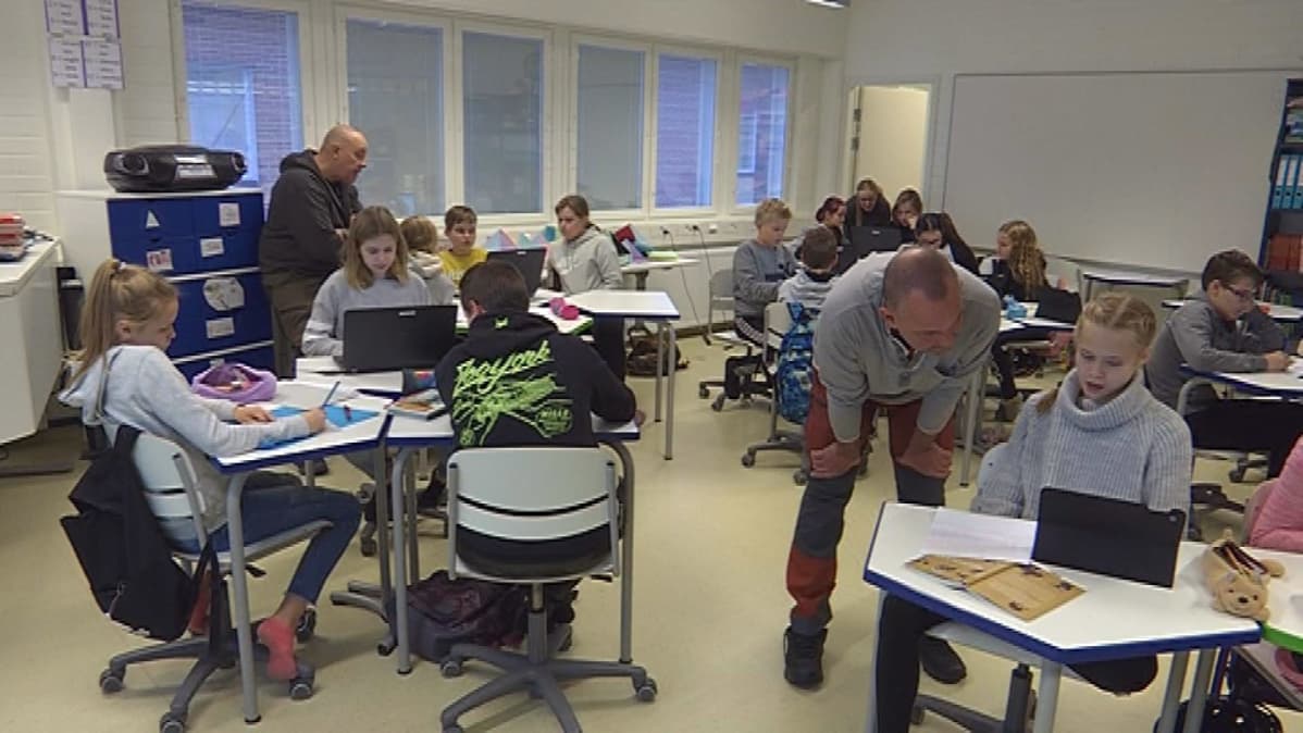 Oppilaita ja aikuisia koululuokassa
