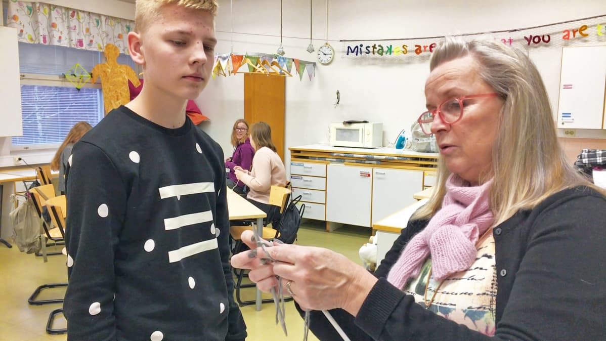 Käsityönopettaja Tiina Tiitinen opastaa Max Sutista villasukan neulomisessa.