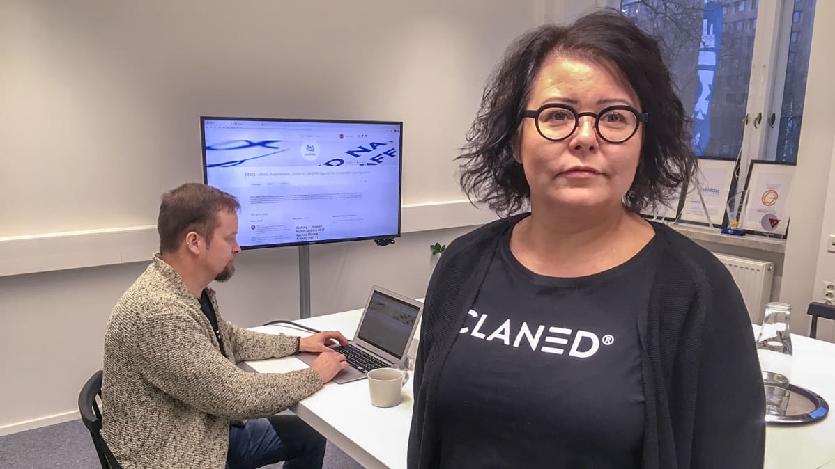 nainen ja taustalla mies tietokoneella