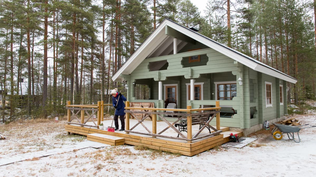 Annikki Lehto lakaisee mökin kuistia.