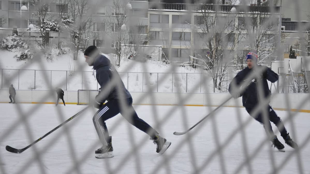 Miehet pelaavat jääkiekkoa Koulukadun kentällä Tampereella.