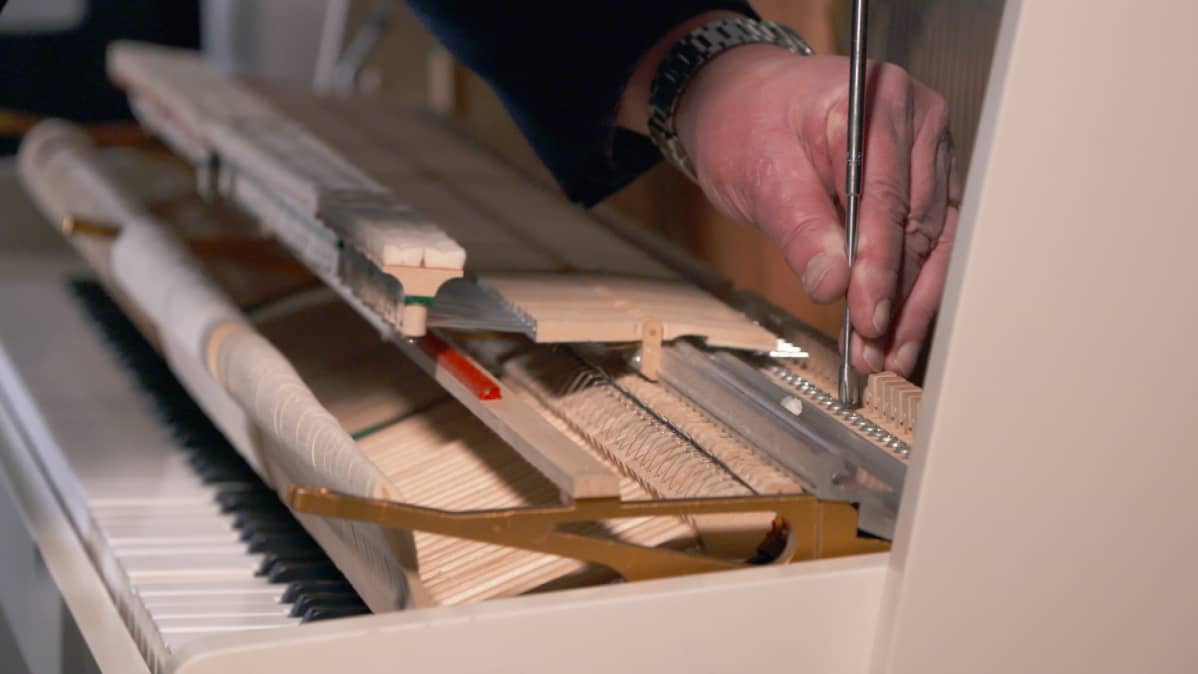 Pianonvirittäjä Pekka Savolainen huoltaa pianoa.
