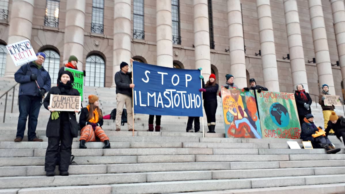 Mielenosoittajia Eduskuntatalon portailla perjantaiaamuna 8. helmikuuta.