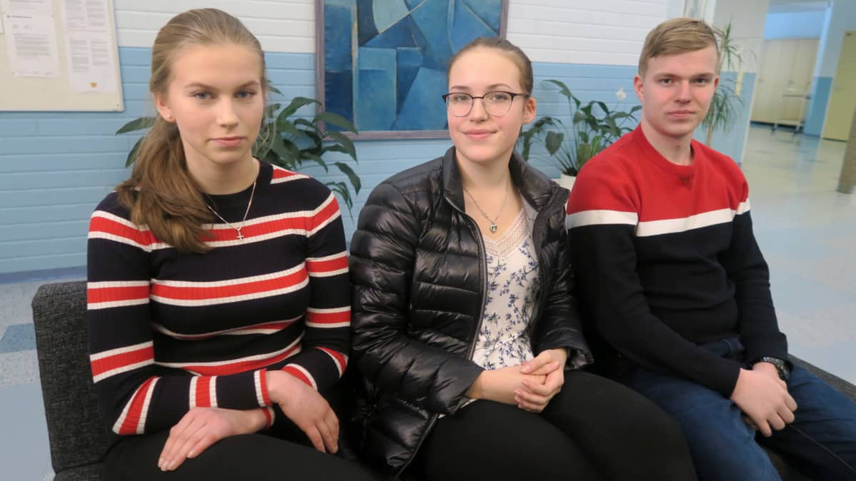 Nuoria lukiolaisia istumassa koulun käytävällä