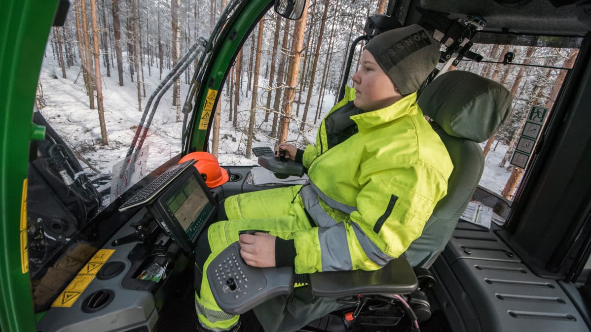 Opiskelija metsäkoneen ohjaamossa.
