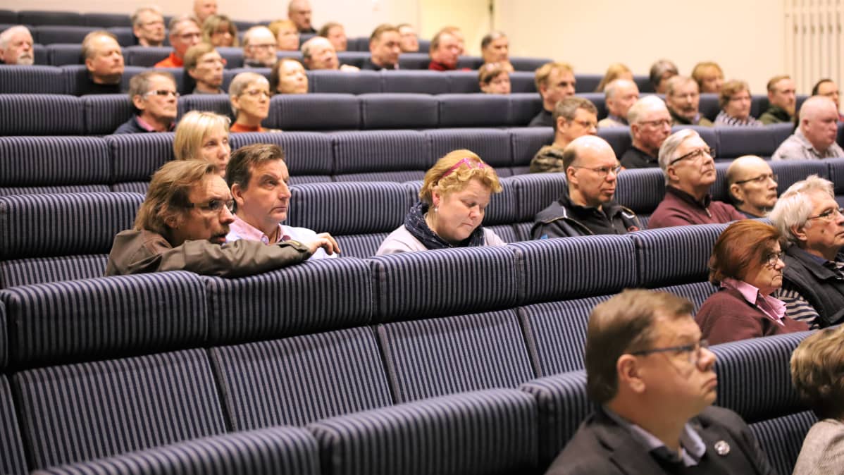 Ihmiset kuuntelevat keskittyneenän koulun audiotoriossa.