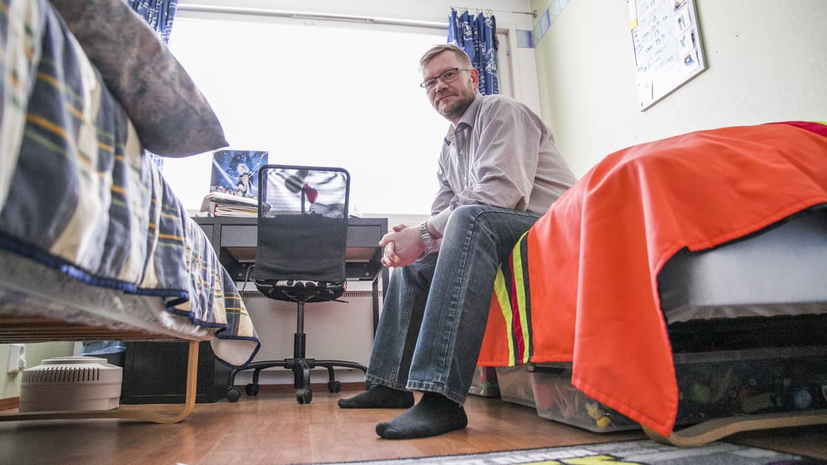 Mies istuu lasten huoneen sängyllä