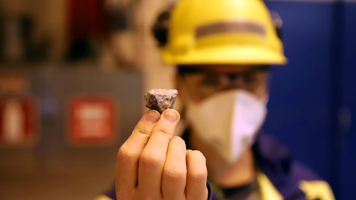 Tytti Pernu pitelee pientä ferrokromimalmikiven kappaletta käsissään.