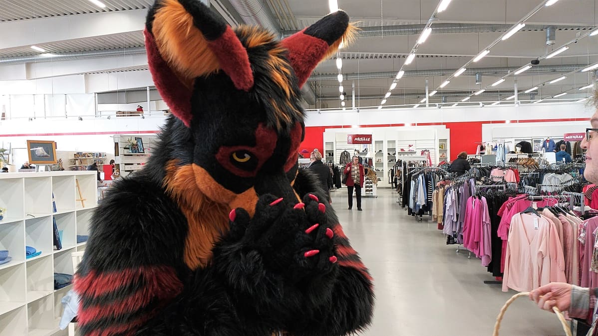 Turripukuun pukeutunut henkilö pitelee kuonoaan lähikuvassa.